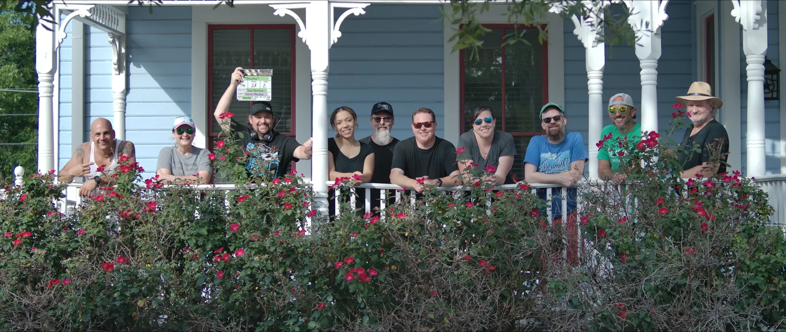 The Ten House Productions cast and crew on a front porch, one holding a film slate
